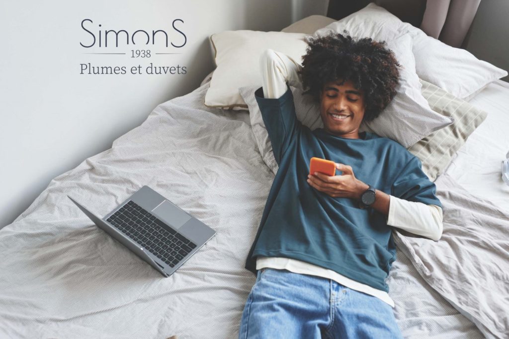 Un homme sur un lit, utilisant un téléphone portable.